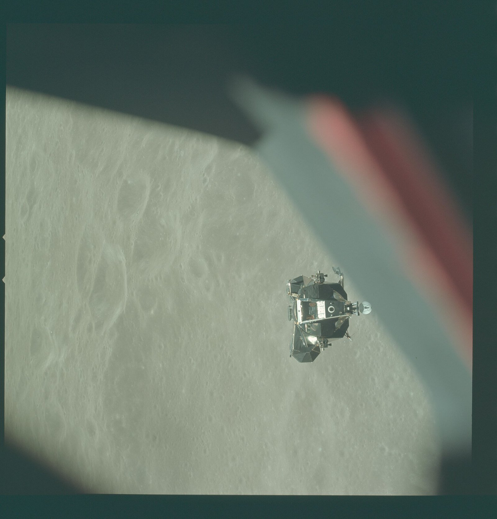 The Apollo 10 lunar module ascent stage, nicknamed Snoopy, approaching the command module in lunar orbit above gray cratered terrain